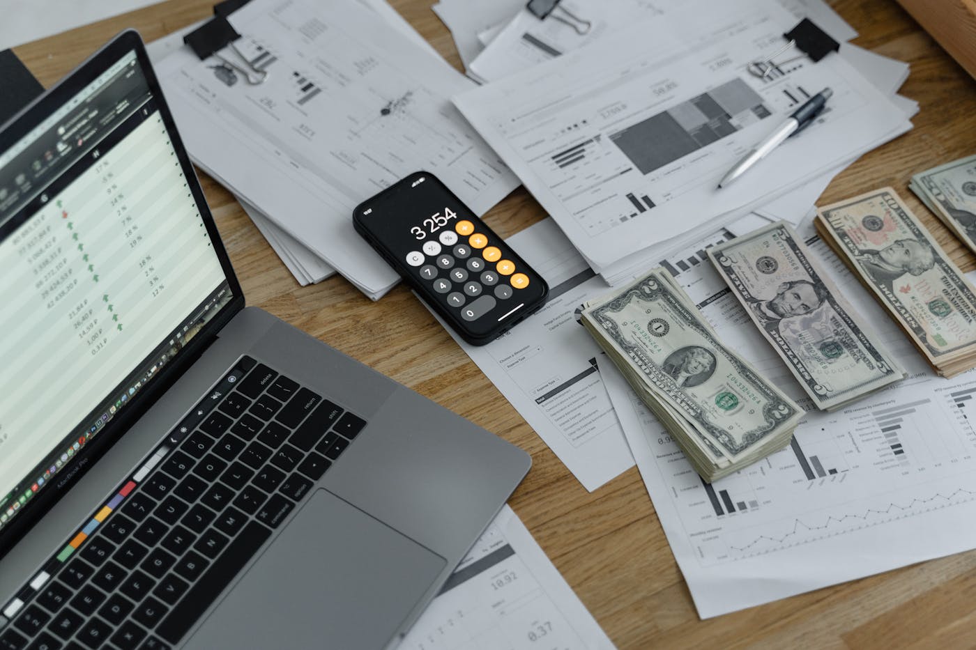 Laptop with spreadsheet, calculator and budget documents on a desk